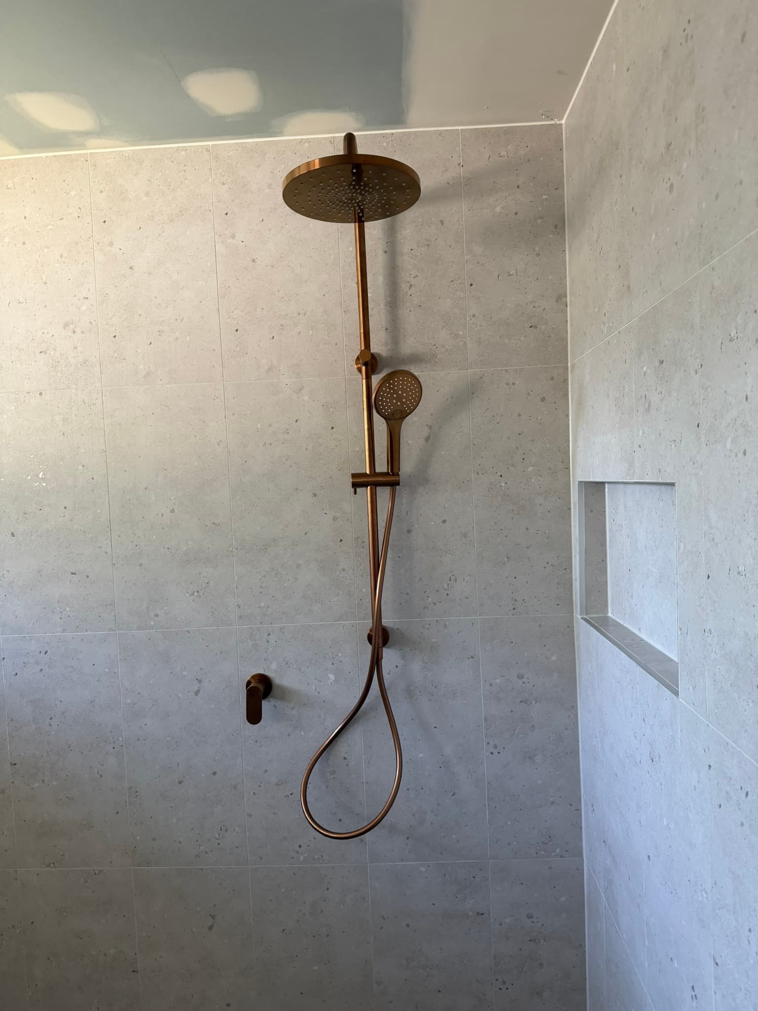 Installed shower head and mixer in a tiled bathroom
