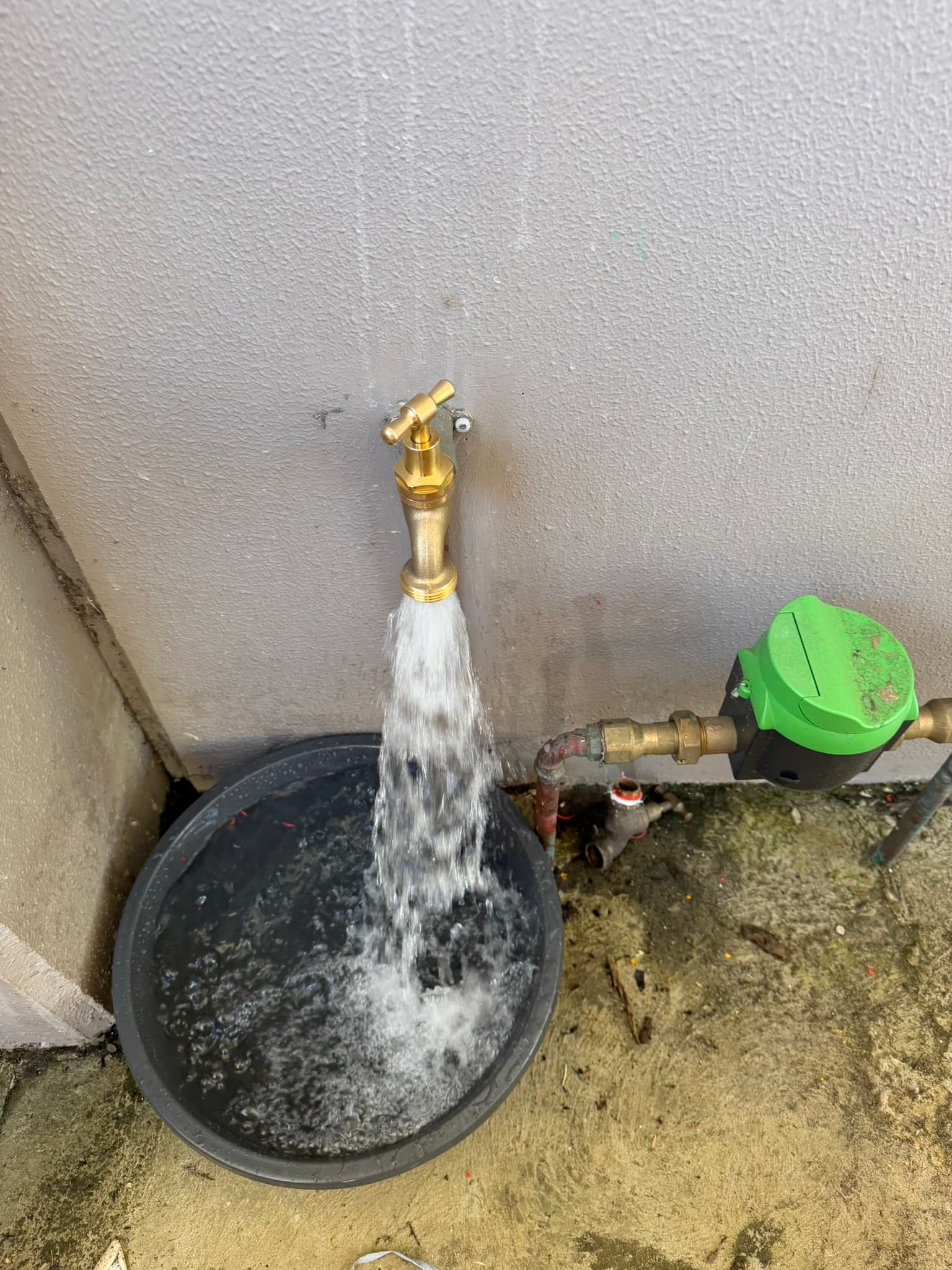 Outdoor tap running water into a bucket during repair work